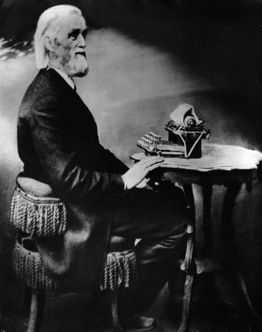 Christopher Sholes sits before his invention, the typewriter. ([Public domain], <a href="https://commons.wikimedia.org/wiki/File%3ASholes_at_his_typewriter.jpg">via Wikimedia Commons</a>)