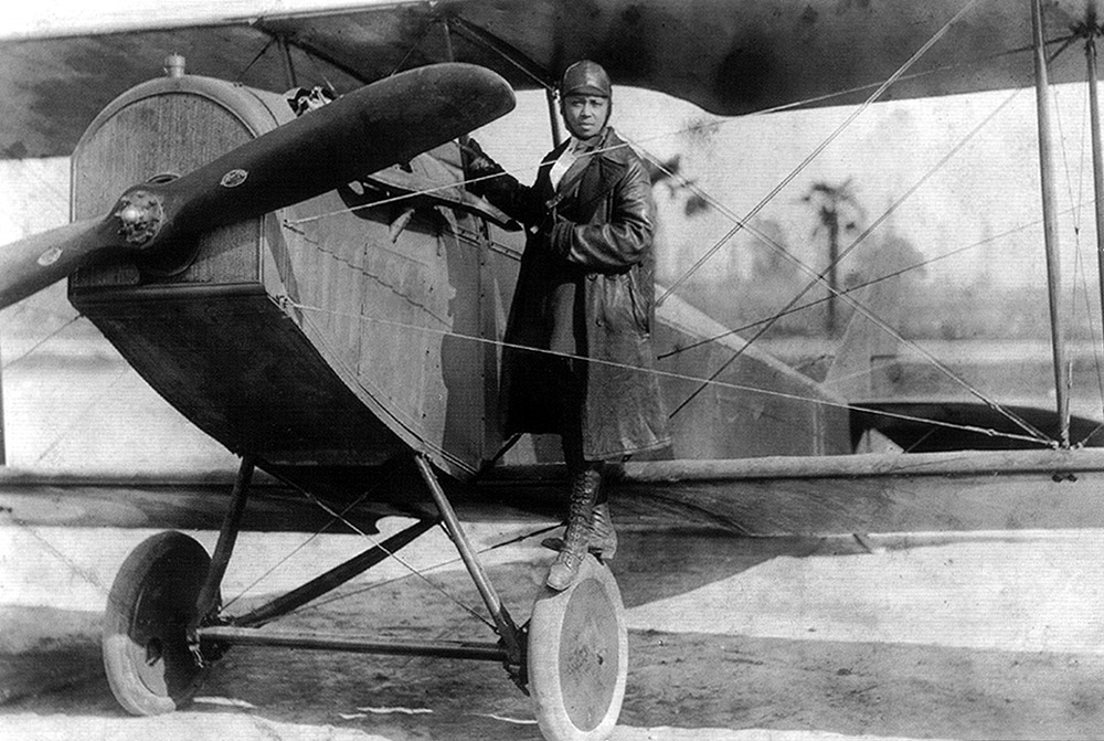 See page for author [Public domain], <a href="https://commons.wikimedia.org/wiki/File%3ABessie_Coleman_and_her_plane_(1922).jpg">via Wikimedia Commons</a>