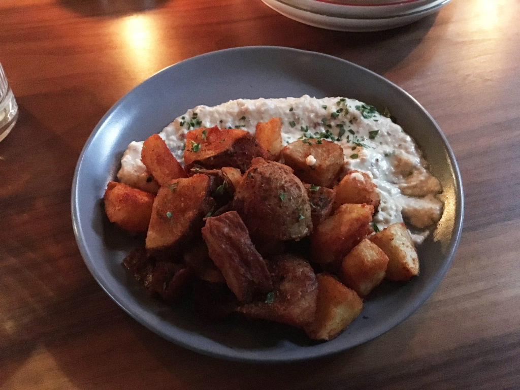 The skordalia is the creamy hummus-like paste seen at the top of the plate, next to the potatoes.